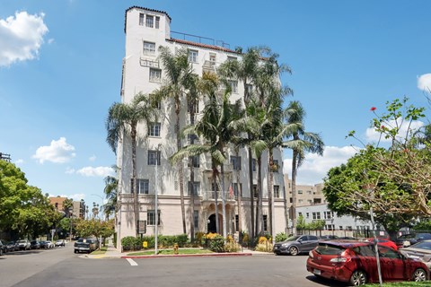 A white building with a red car parked in front of it.