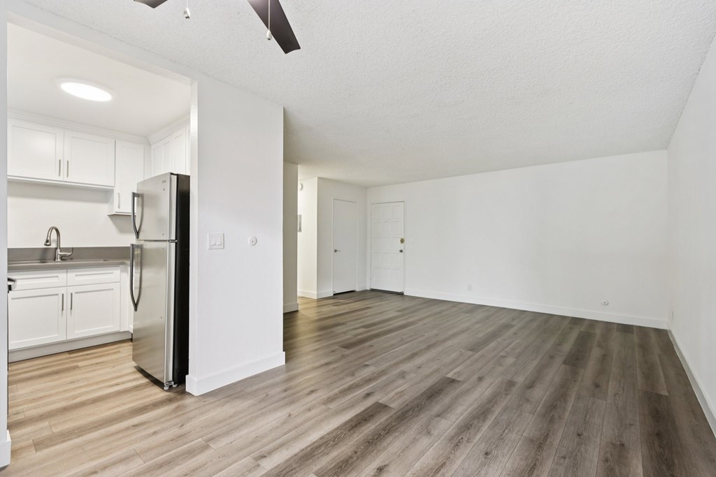 A kitchen with a refrigerator, sink, and cabinets.