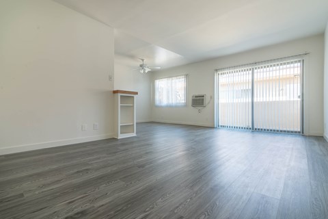 A spacious room with wooden flooring and white walls.