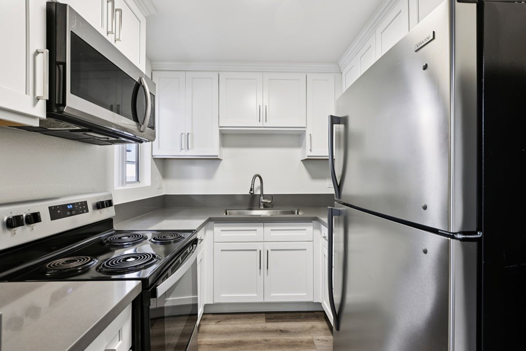 A modern kitchen with white cabinets and stainless steel appliances.