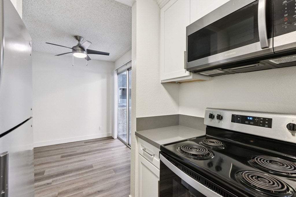 A modern kitchen with a stove, microwave, and fan.
