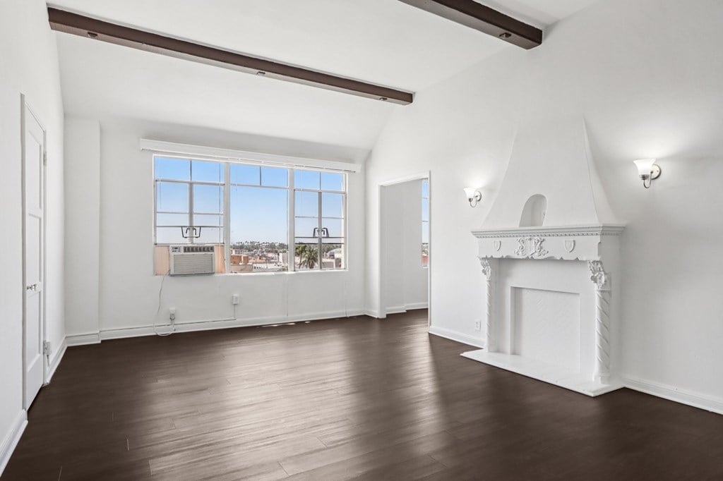 A large empty room with a fireplace and wooden floors.