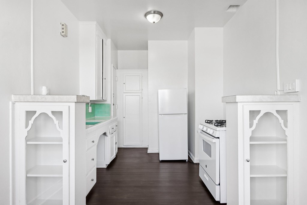 A white kitchen with a wood floor and white appliances.