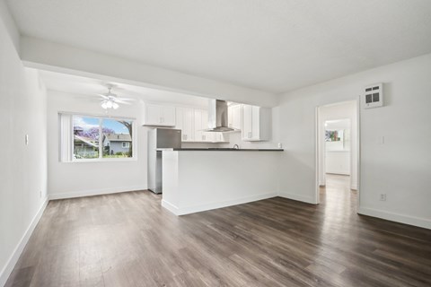 A spacious room with wooden flooring and white walls.