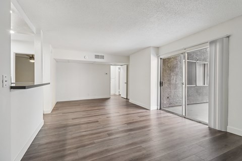 A spacious room with wood flooring and white walls.