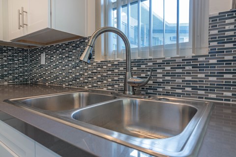 A modern kitchen with a stainless steel sink and a chrome faucet.