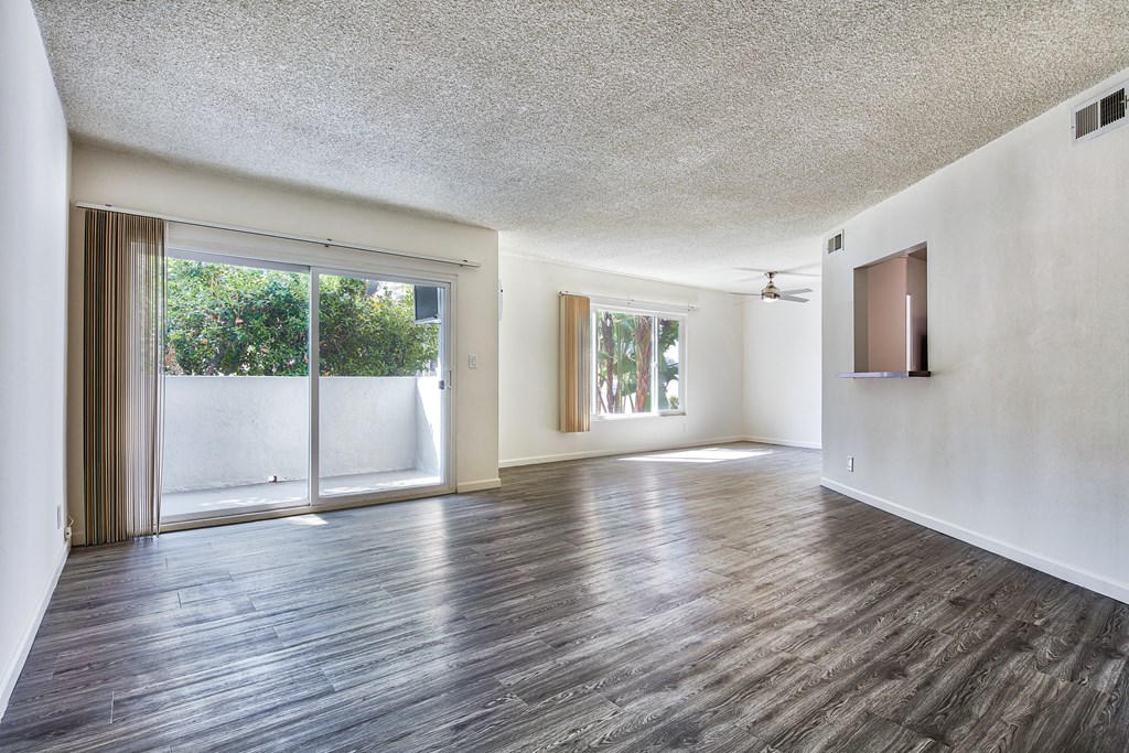 an empty living room with wood flooring and a sliding glass door