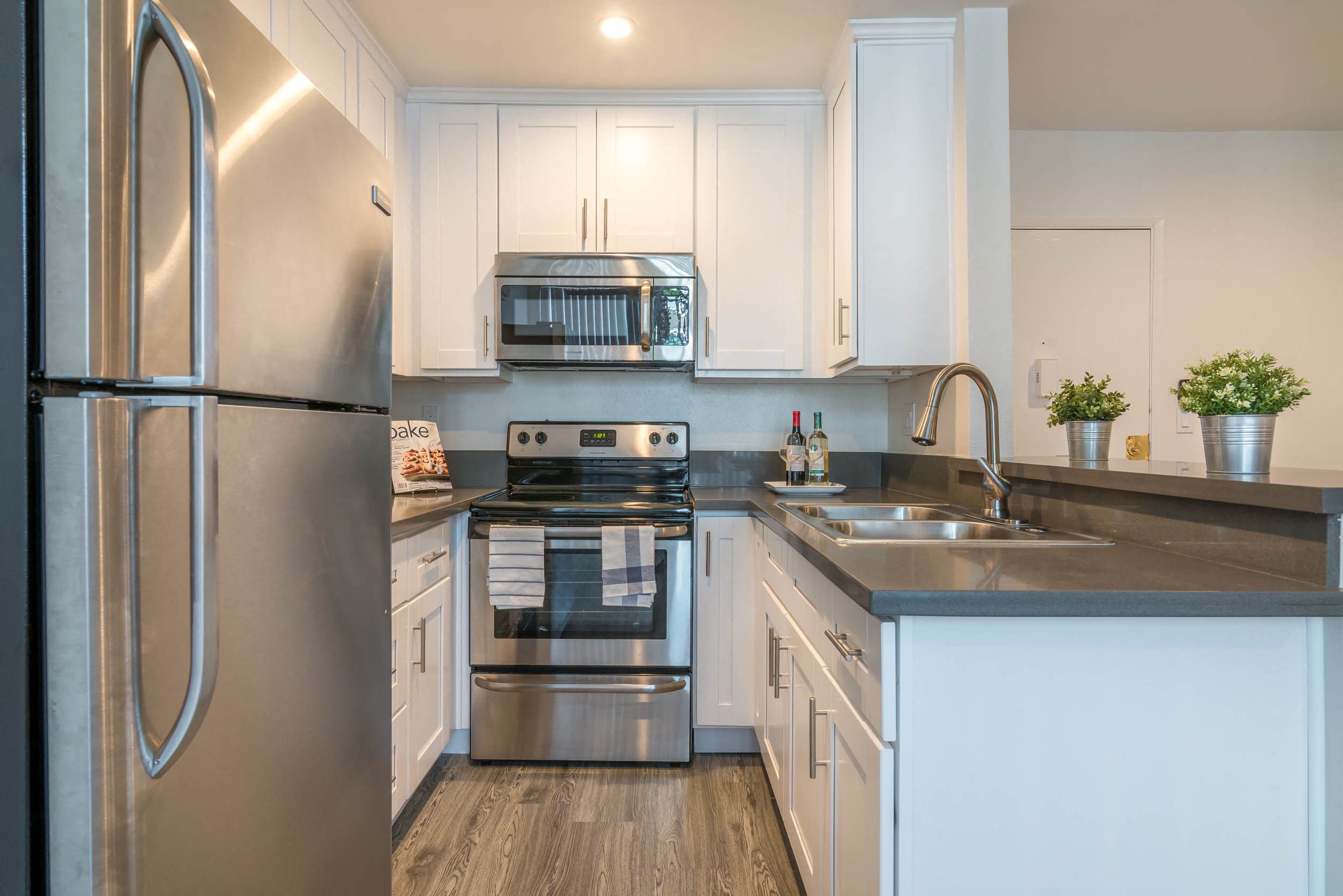 A modern kitchen with a stainless steel refrigerator and white cabinets.