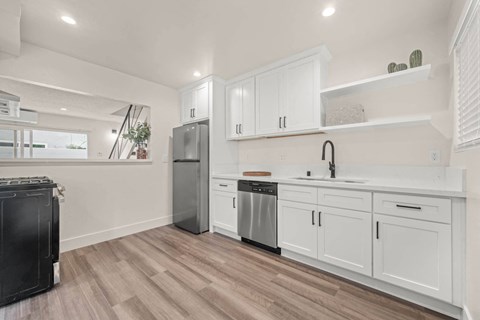 a white kitchen with white cabinets and stainless steel appliances