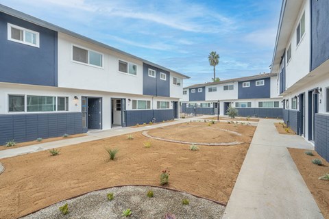 A courtyard surrounded by apartment buildings with a clear blue sky above.