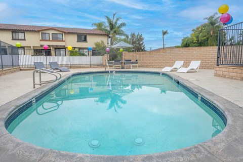 A small pool with a metal fence and a house in the background.