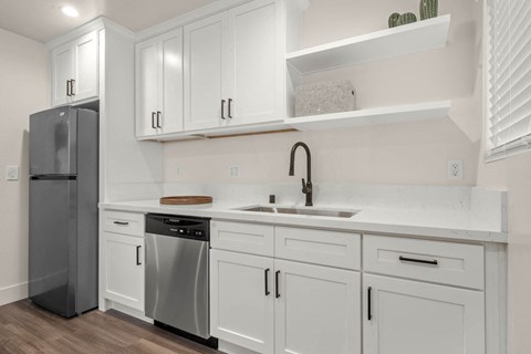 A kitchen with white cabinets and a black refrigerator.