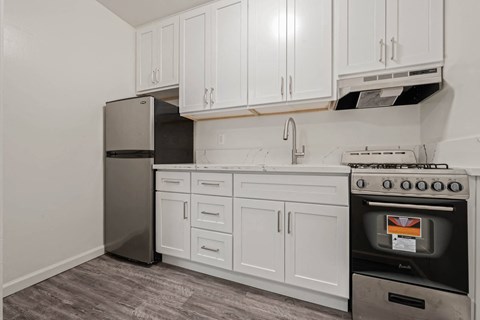 A kitchen with white cabinets and a black fridge.