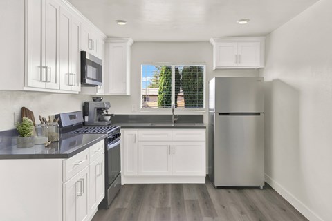 A modern kitchen with white cabinets and a stainless steel refrigerator.