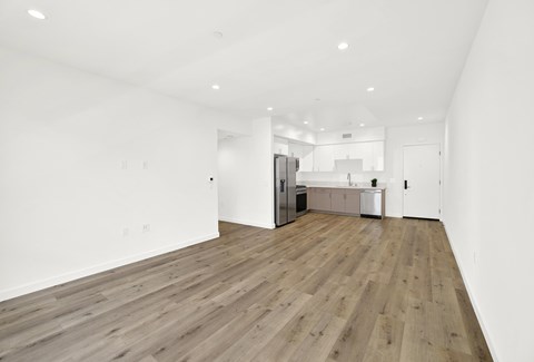 A spacious room with wooden flooring and white walls.