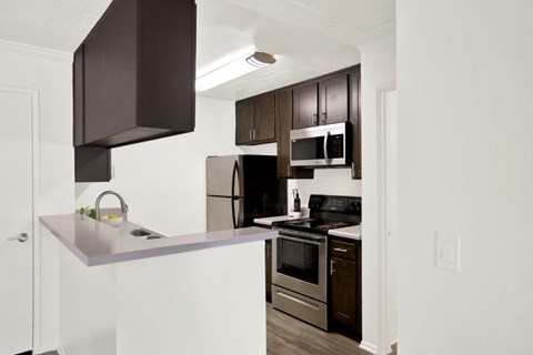 A kitchen with a white counter top and stainless steel appliances.