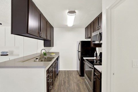 A kitchen with dark brown cabinets and white appliances.