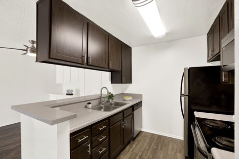 A kitchen with dark brown cabinets and a black refrigerator.