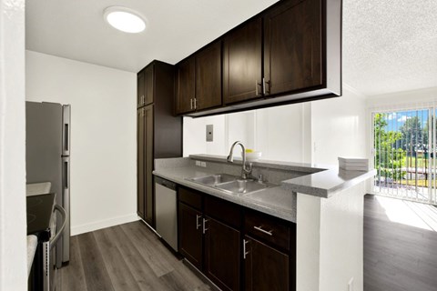 A kitchen with dark wood cabinets and a white sink.