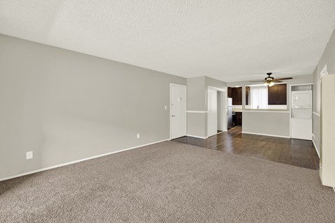 A spacious living room with a carpeted floor and a ceiling fan.