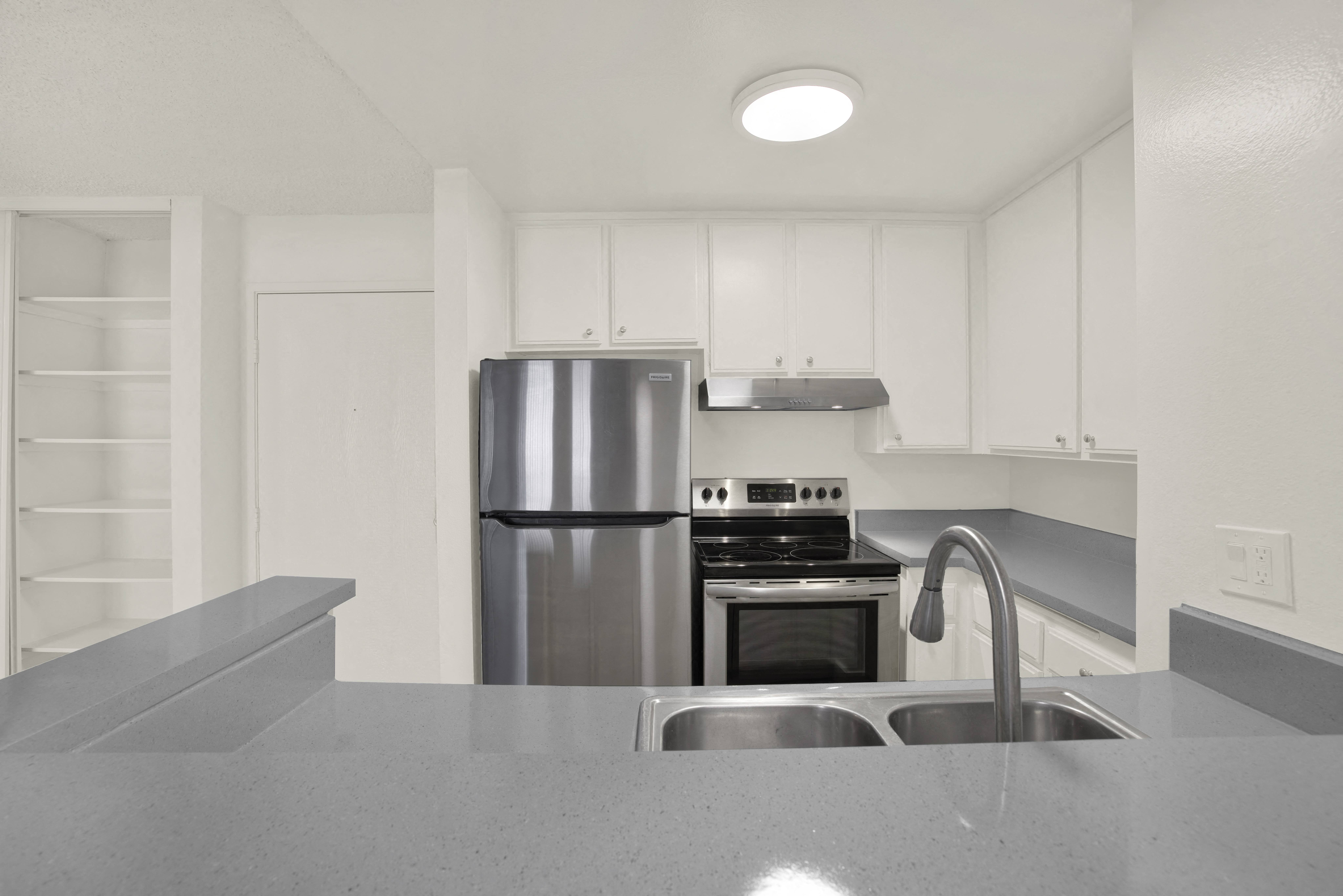 A modern kitchen with a stainless steel refrigerator and a sink.