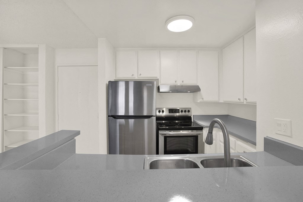 A modern kitchen with a stainless steel refrigerator and a sink.