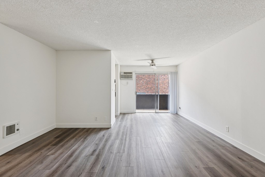 A room with a ceiling fan and a door leading to a balcony.