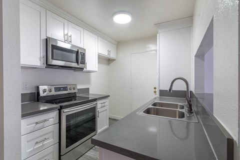 kitchen with white cabinets, built-in microwave and range
