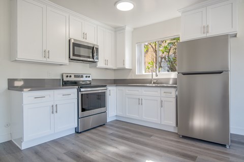 A kitchen with white cabinets and a stainless steel refrigerator.