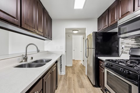 A kitchen with dark brown cabinets and a black refrigerator.
