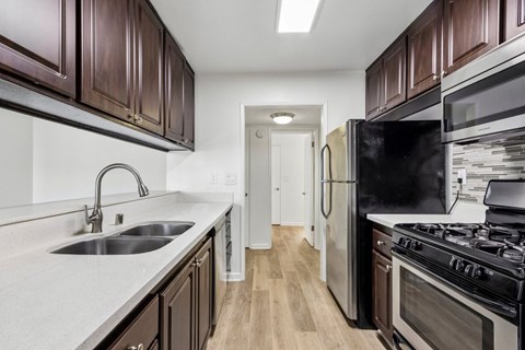 A kitchen with dark brown cabinets and a black refrigerator.