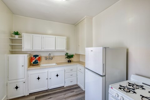 A white kitchen with a stove, sink, and cabinets.