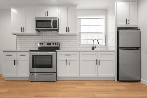 A modern kitchen with white cabinets and stainless steel appliances.