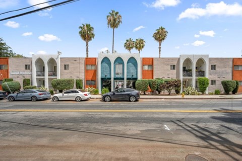 A building with orange and beige walls with palm trees in the background.