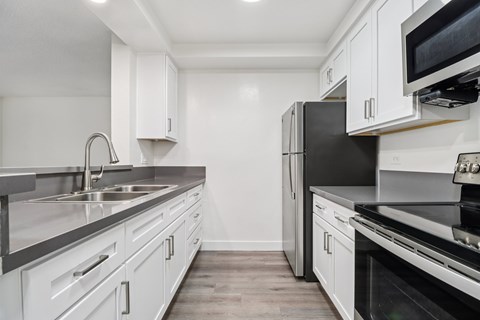 A kitchen with black appliances and white cabinets.