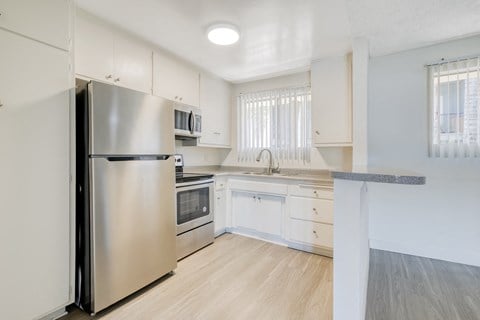 a renovated kitchen with stainless steel appliances and white cabinets