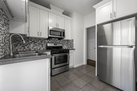 A kitchen with a refrigerator, sink, and stove.
