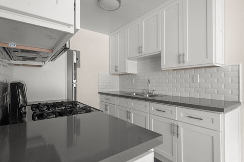 a kitchen with white cabinets and black counter tops