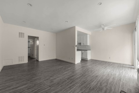 A spacious room with wooden flooring and a ceiling fan.