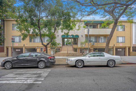 Two cars parked in front of a building with the number 7558 on it.
