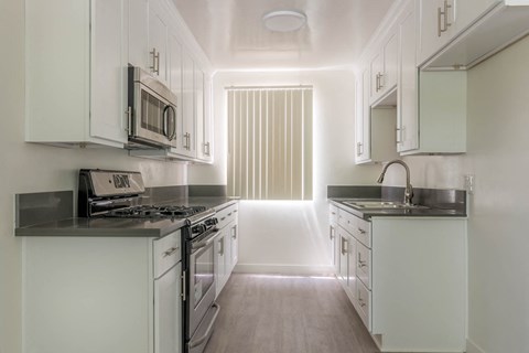 A kitchen with white cabinets and a black countertop.