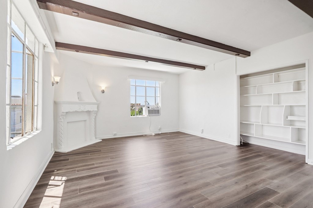 A large empty room with wooden floors and white walls.