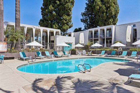 A swimming pool surrounded by lounge chairs and umbrellas.