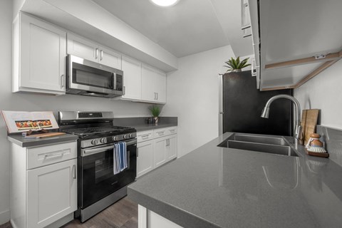 A kitchen with a black countertop and white cabinets.
