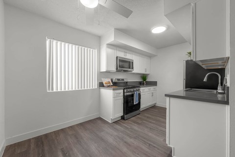 A modern kitchen with white cabinets and a wooden floor.