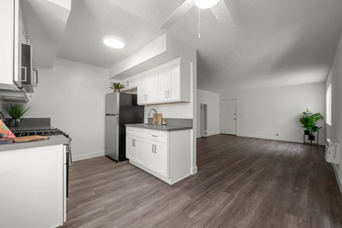 A modern kitchen with white appliances and wooden floors.