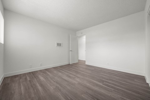 A room with wooden flooring and white walls.