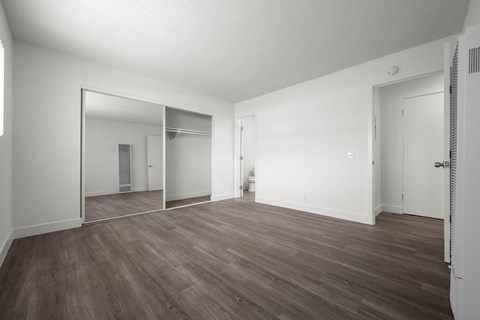 A large empty room with wooden floors and white walls.