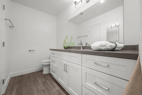 A bathroom with white cabinets and a white toilet.
