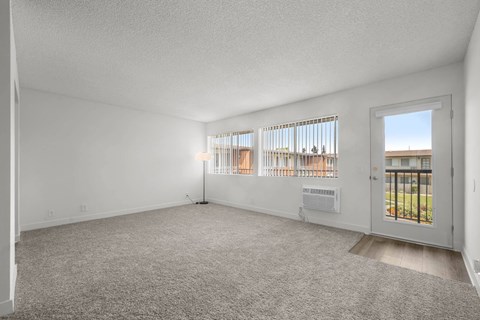 A room with a carpeted floor and a door leading to a balcony.